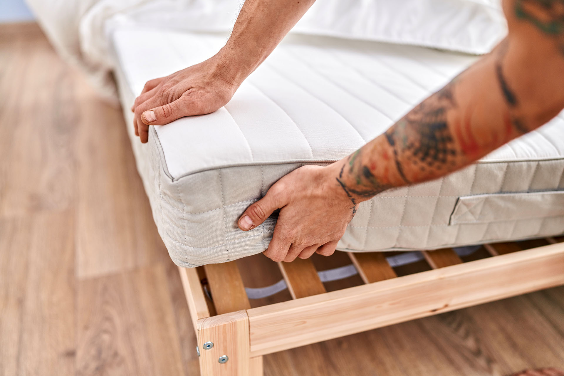 Young man holding mattress at bedroom