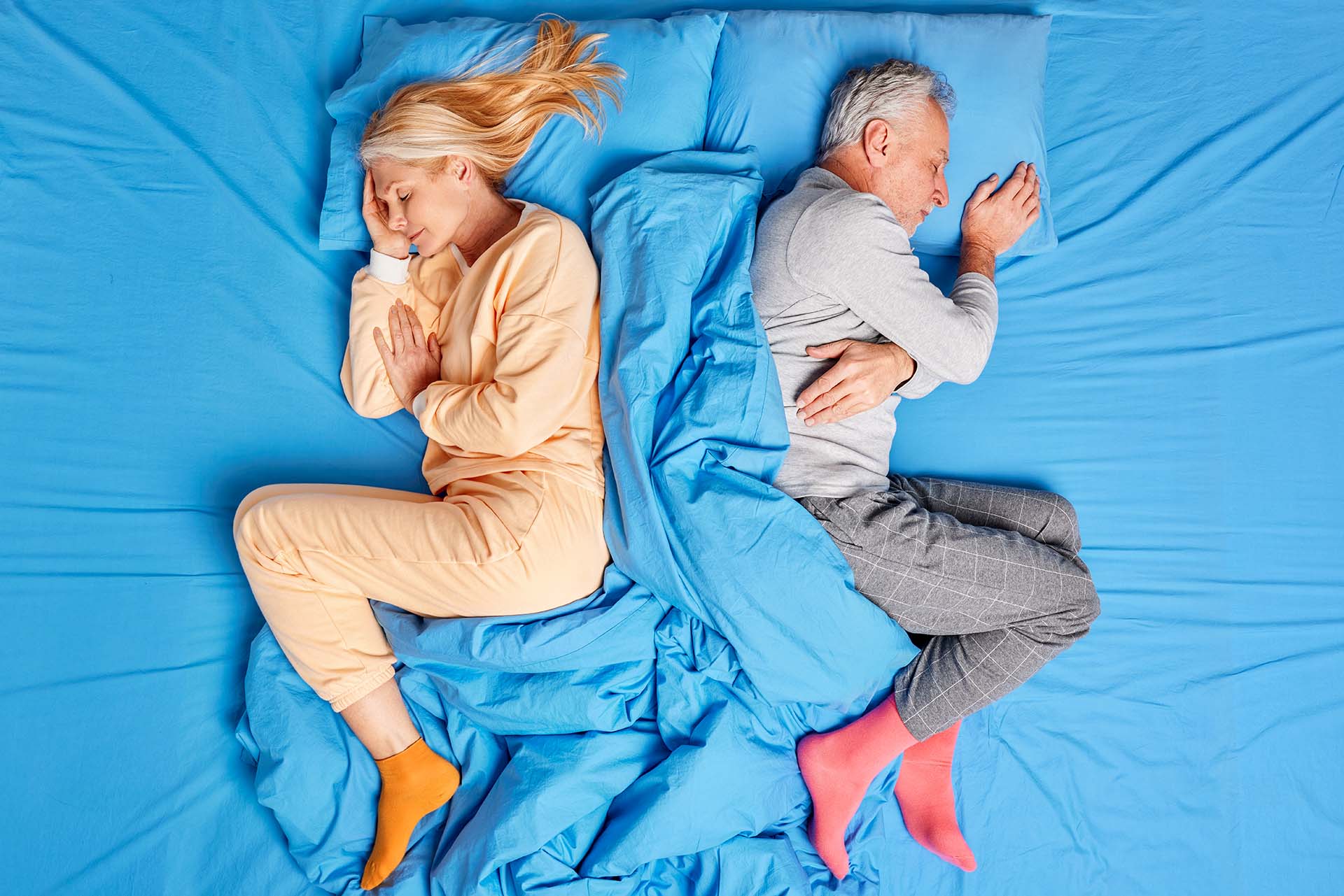 Above view of married old couple sleep deeply lying back to each other in comfortable bed wear soft pajamas have good rest after hard working day enjoy cozy atmosphere. People sleeping concept