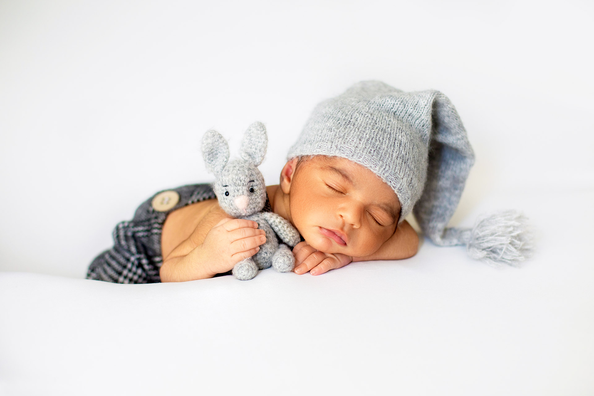 little infant sleeping with cute grey hat and with toy rabbit in